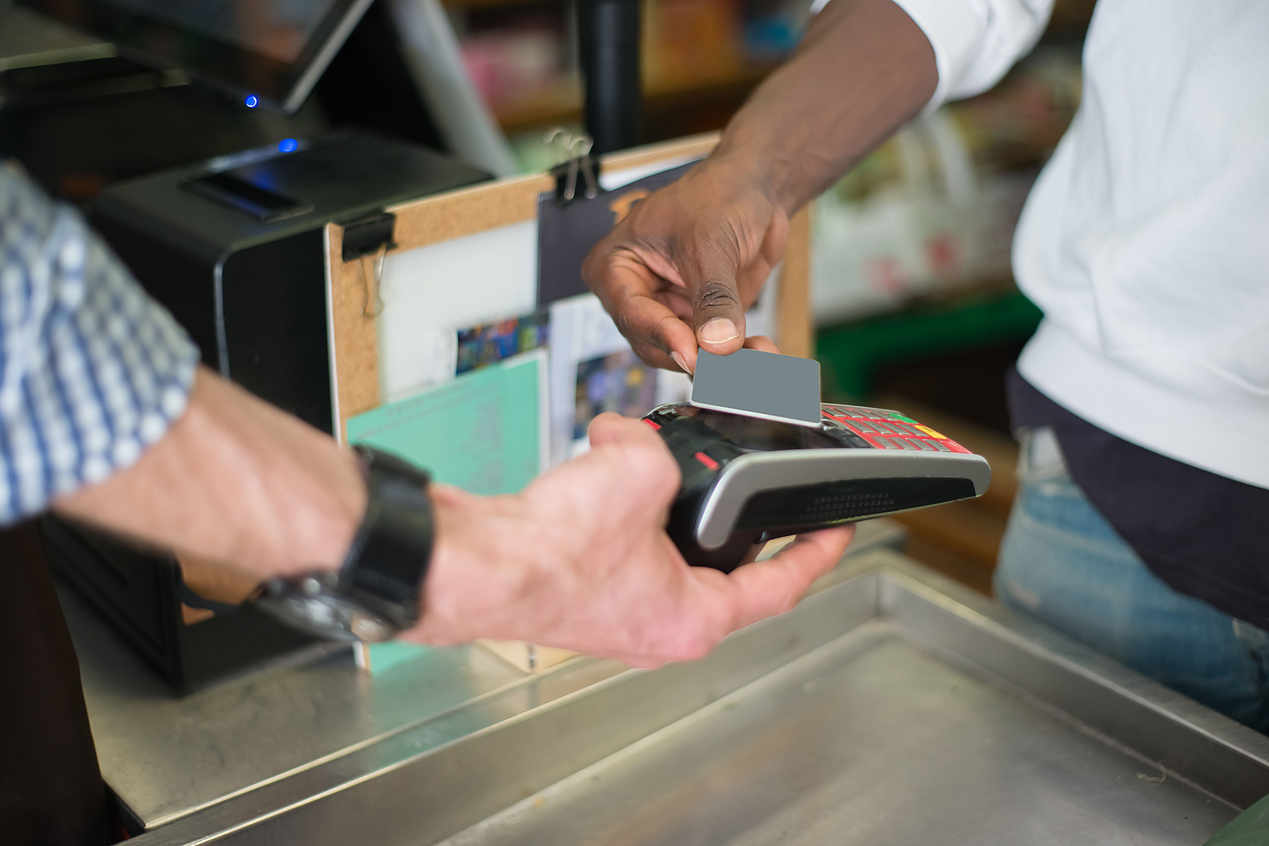 Hands using a card terminal at a business counter
